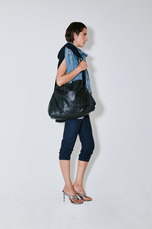 Woman holding a black leather bag against a white background