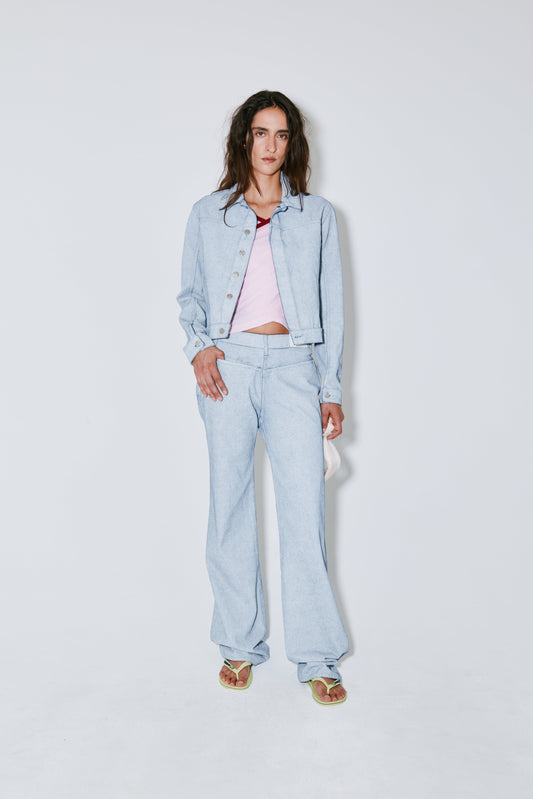 Person wearing a light blue denim outfit on a white background